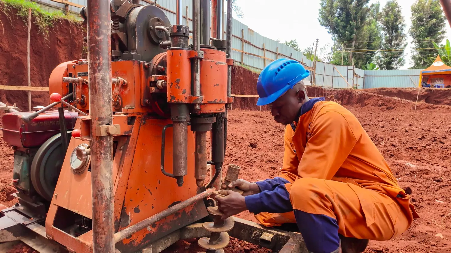 An engineer examining a soil core sample beside the drilling rig