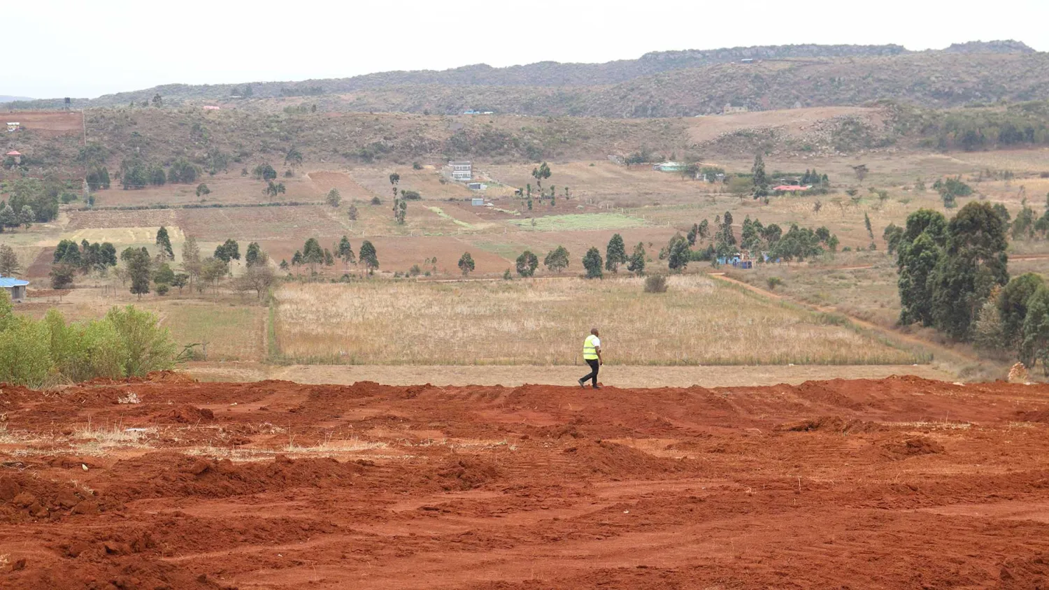 A surveyor walking freshly graded earth on a MilikiSpace site